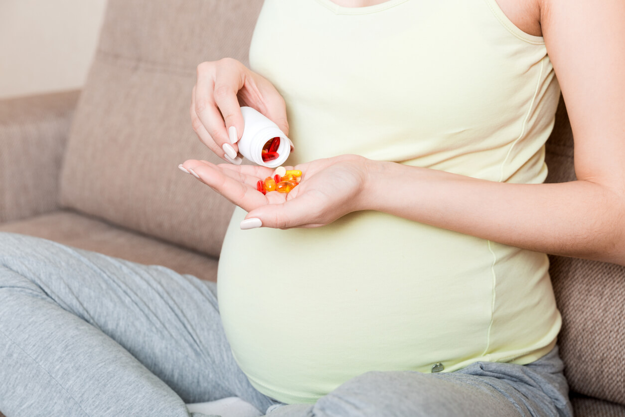 A pregnant woman pouring pills into her hand.