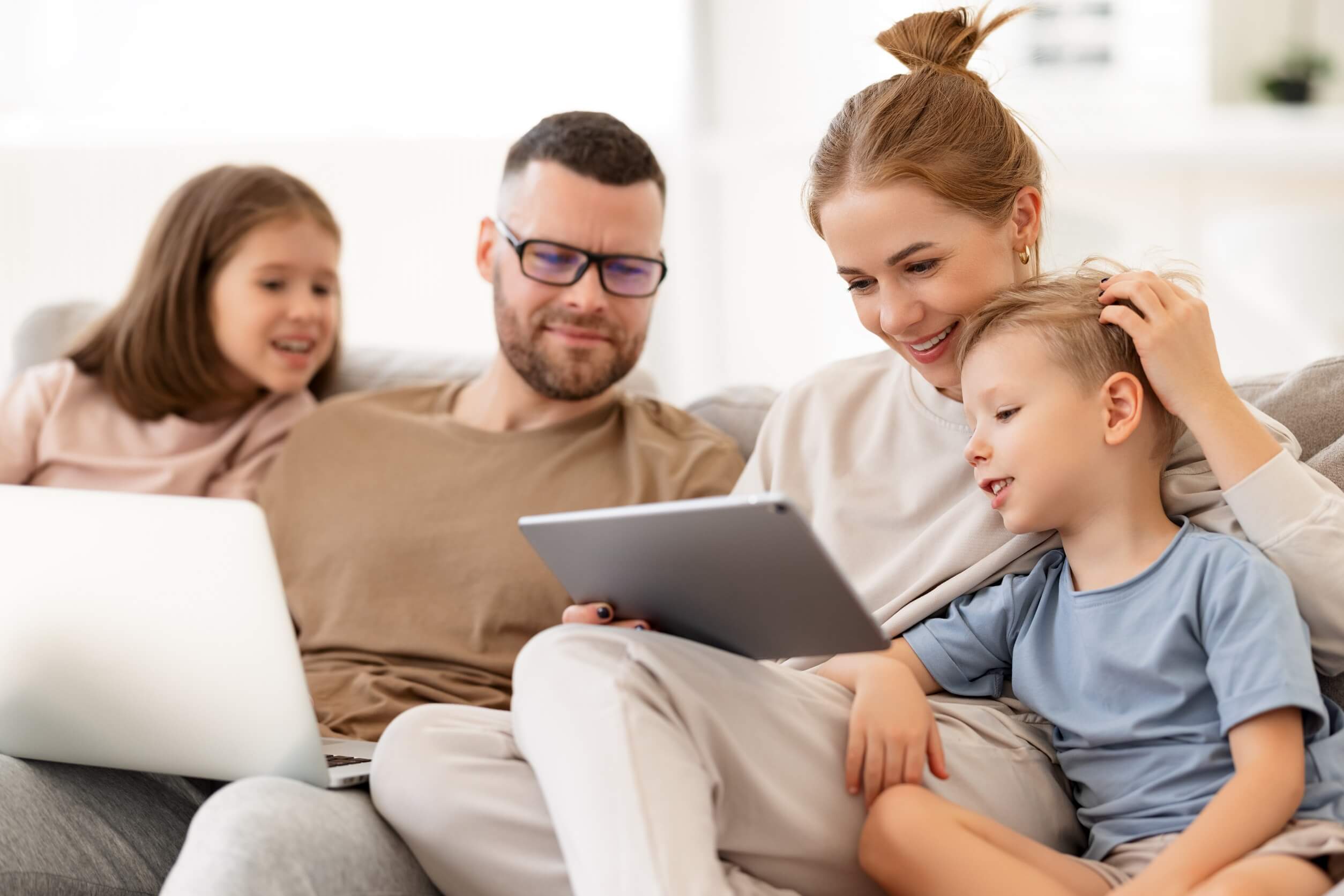 Parents watching something on a tablet with their children.