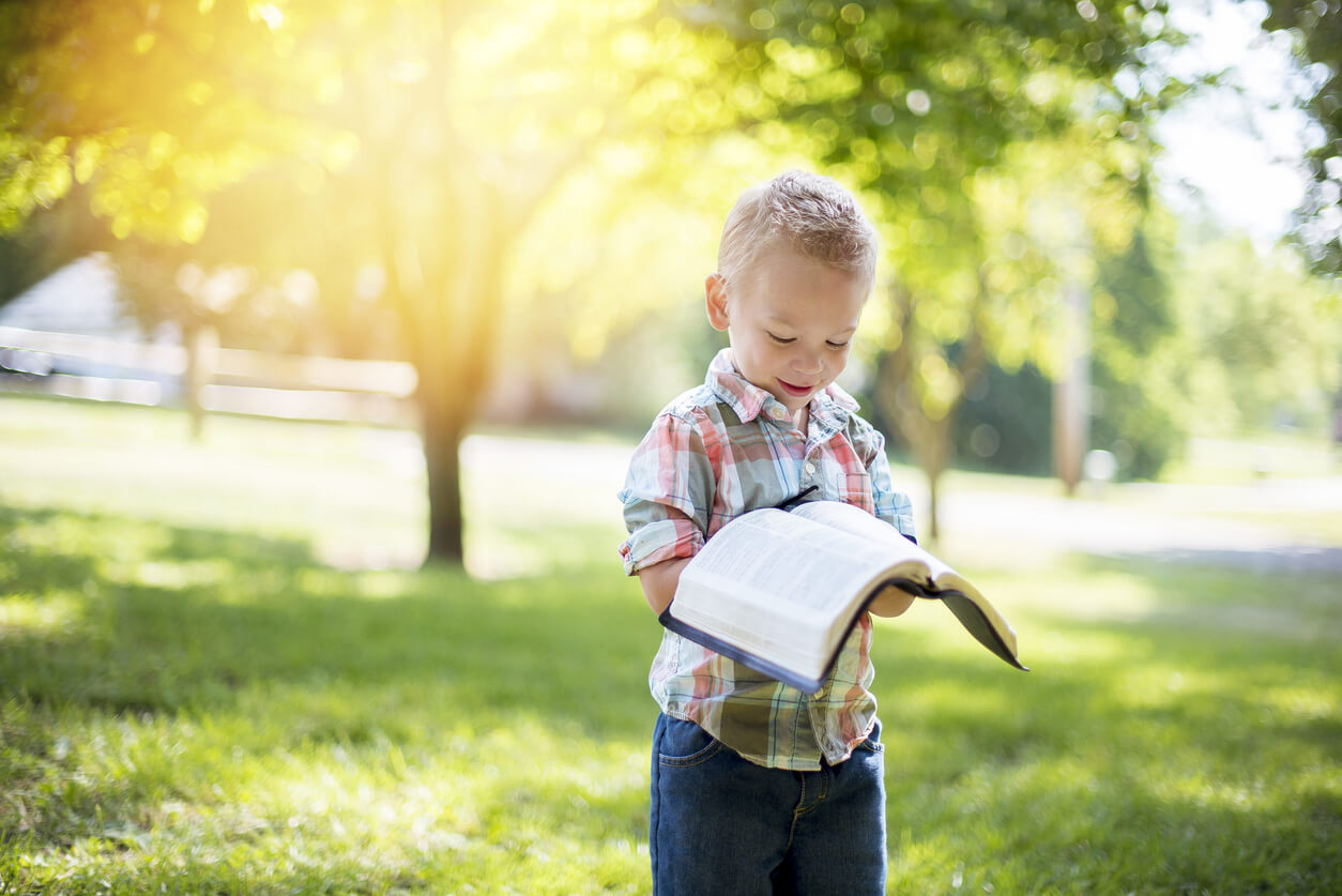 A small child looking at an open Bible.