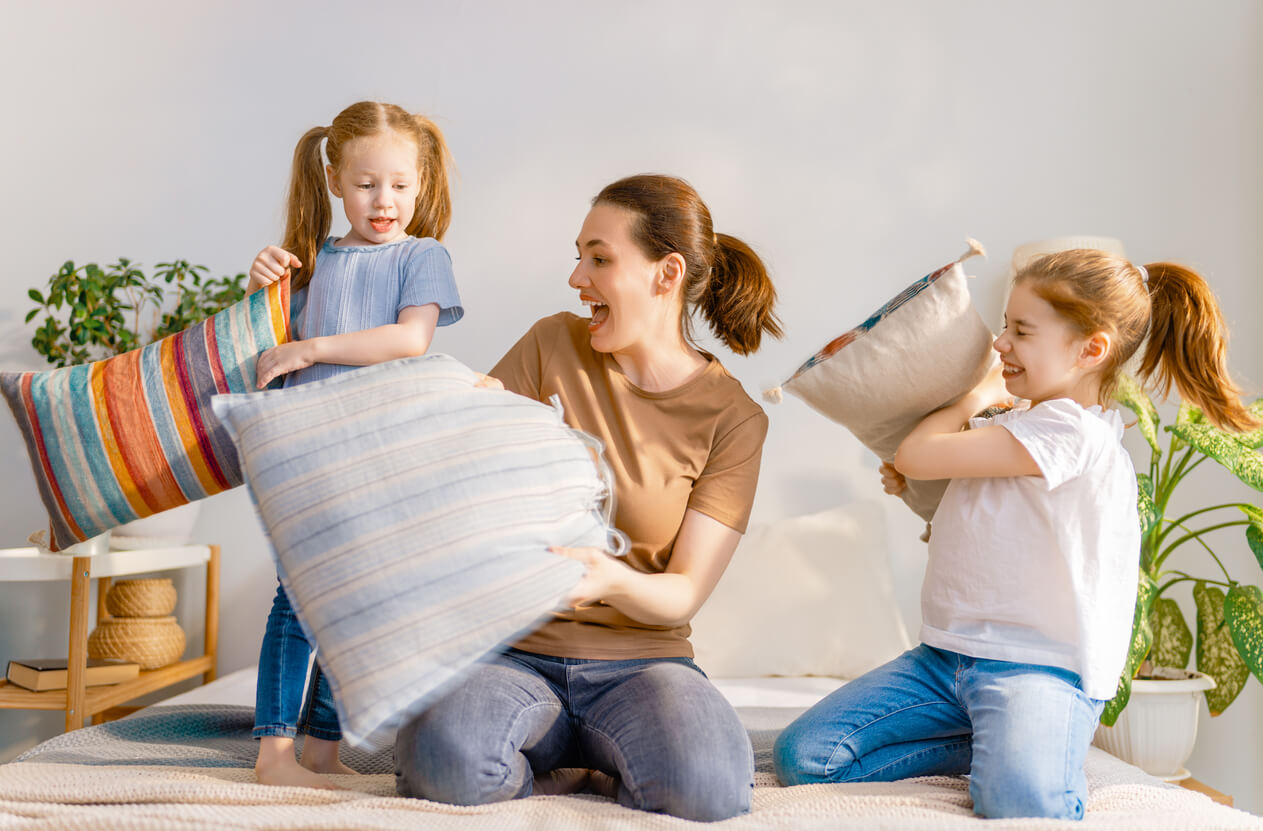 A mother having a pillow fight with her daughters.