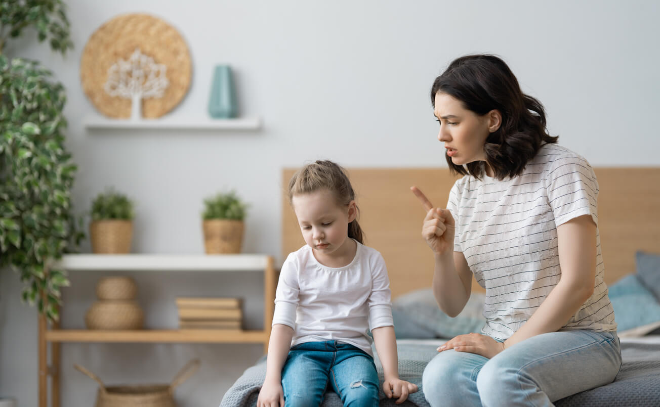 A mother shaking her finger at her young daughter.