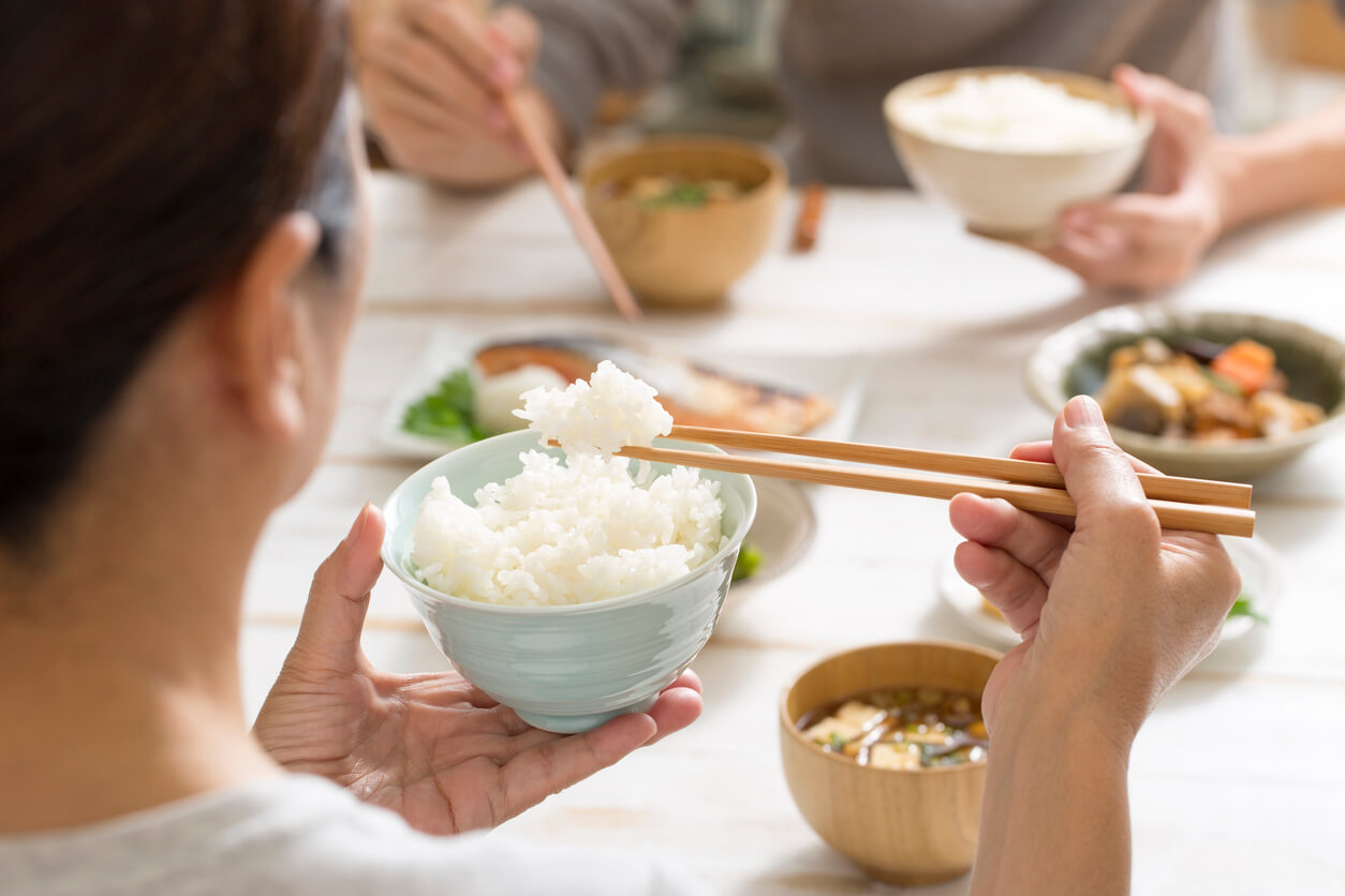 A woman eating white rice with chopsticks.