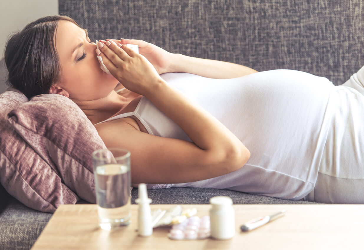 mujer gripe embarazada en el sillon sala de su casa