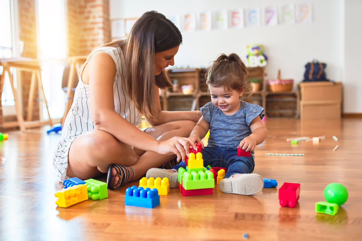 A mother and daughter sitting on the floor building with blocks.