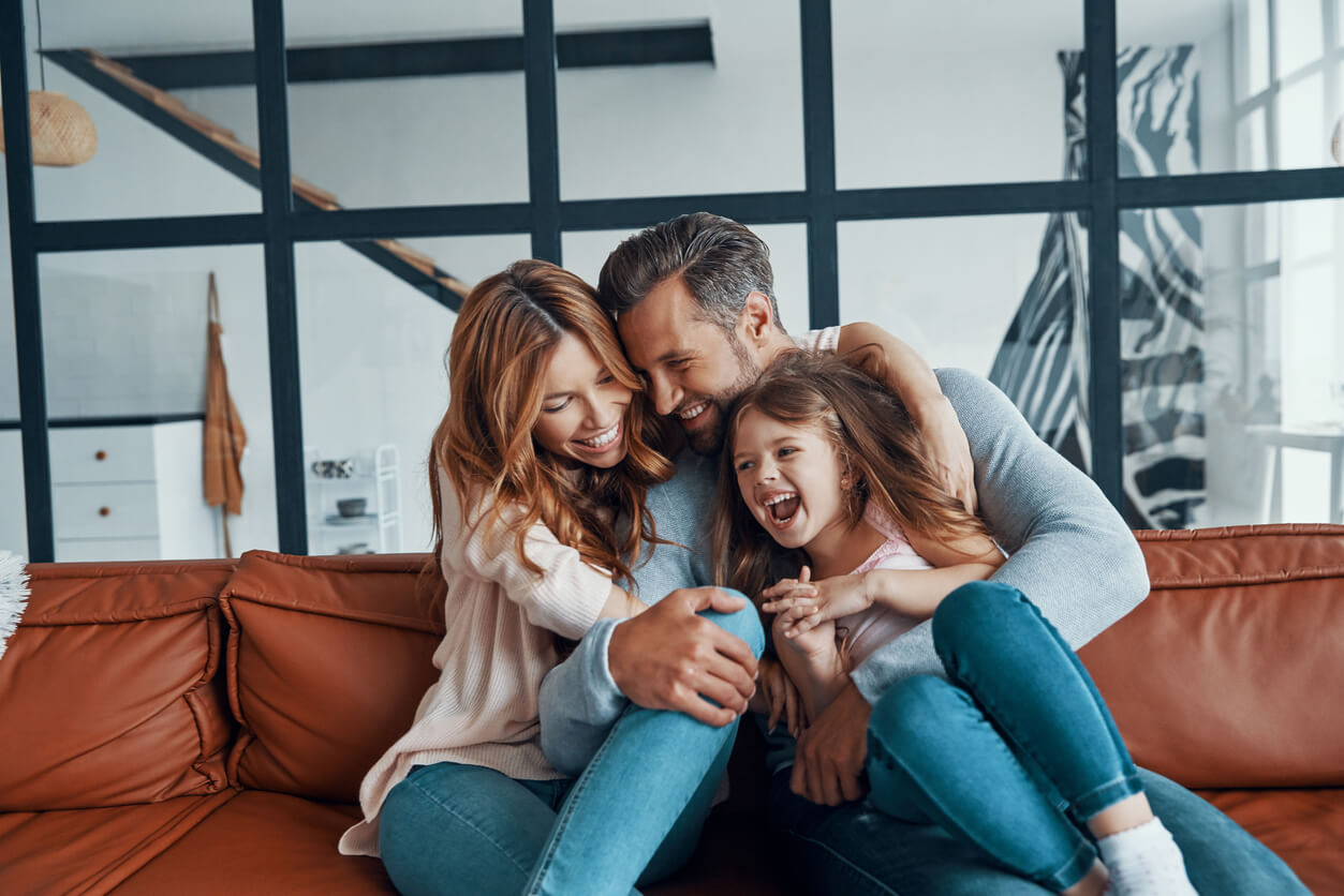 Parents hugging their daughter and smiling.