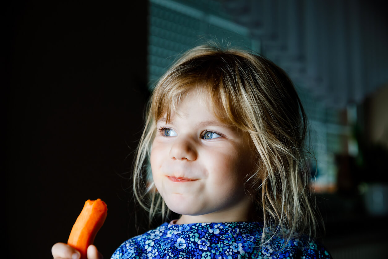 Une jeune fille qui mange dune carotte. 