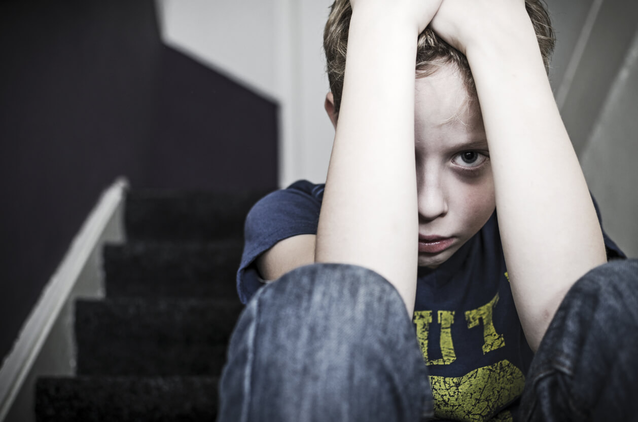 Un enfant qui se cache derrière ses mains. 