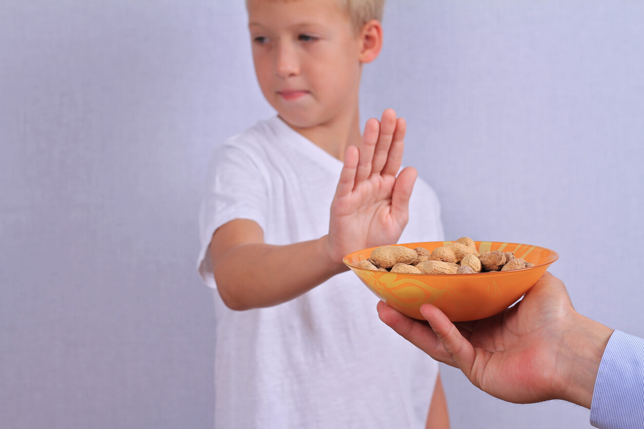 A child refusing a bowl of peanuts.