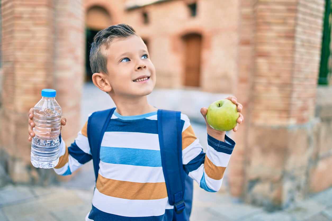 Un enfant avec une pomme et une bouteille d'eau. 
