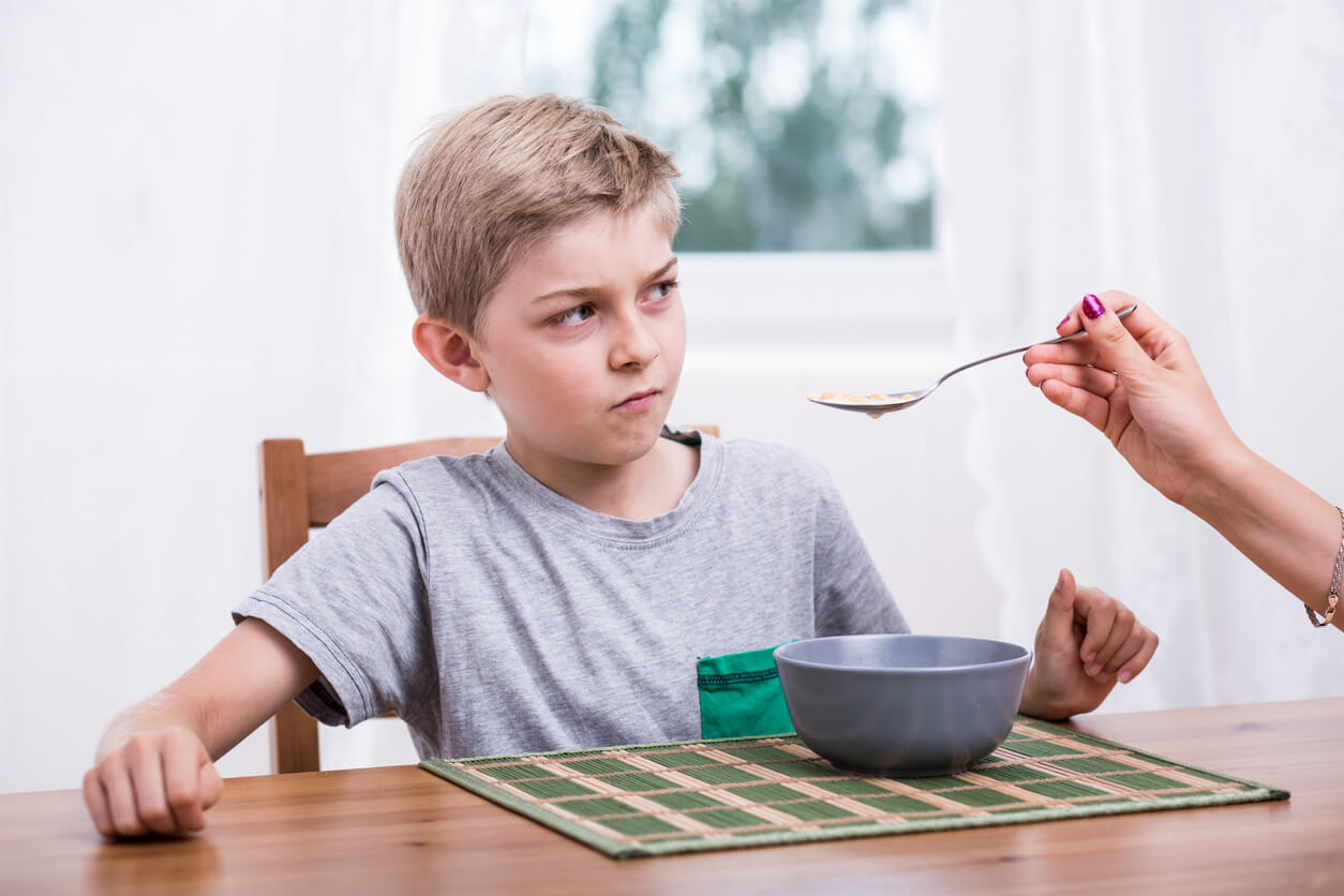 A boy refusing a spoonful of food.