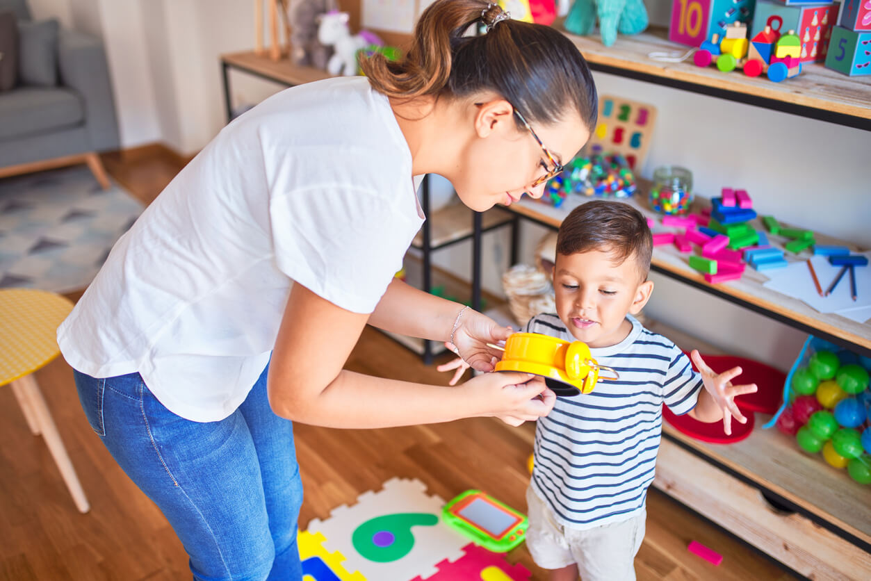 A woman showing a preschooler a toy clock.