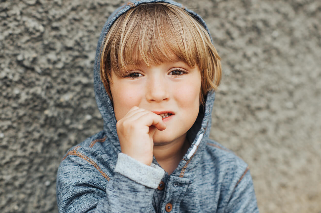 A frightened boy biting his nails.