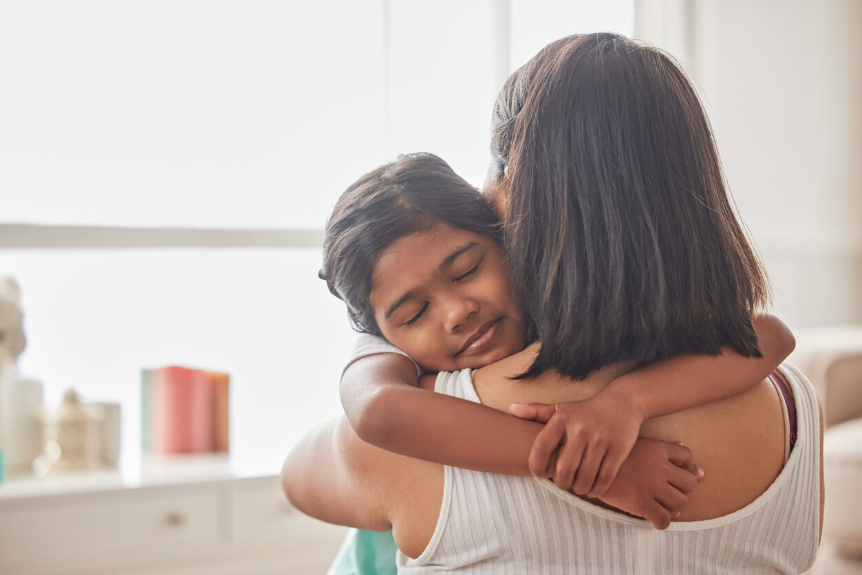 A young girl giving her mother a warm embrace.