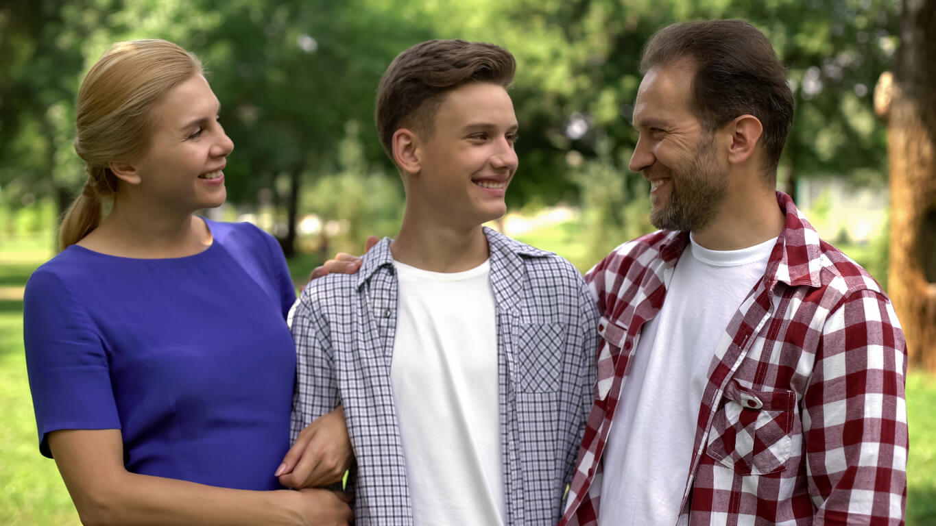 Parents embracing and smiling at their son.