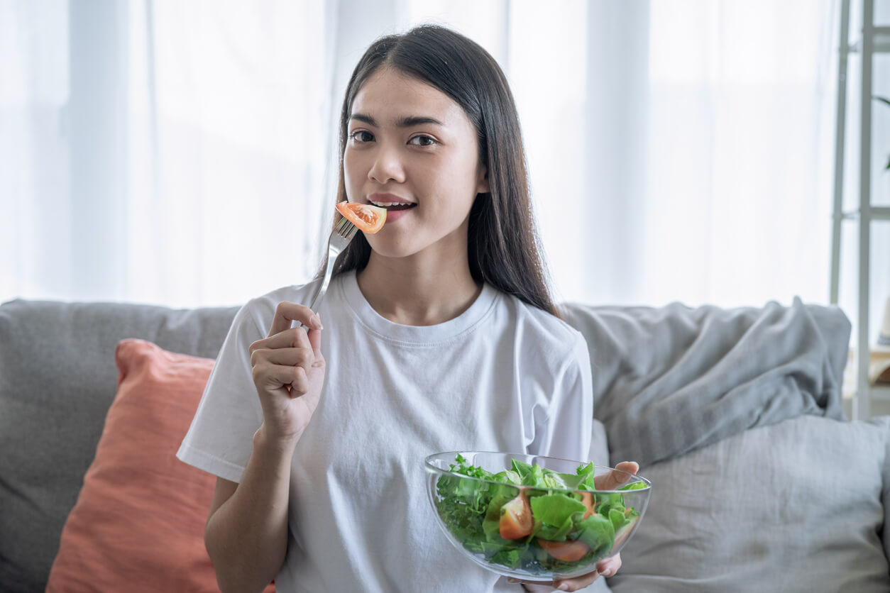 An Asian woman eating a salad.