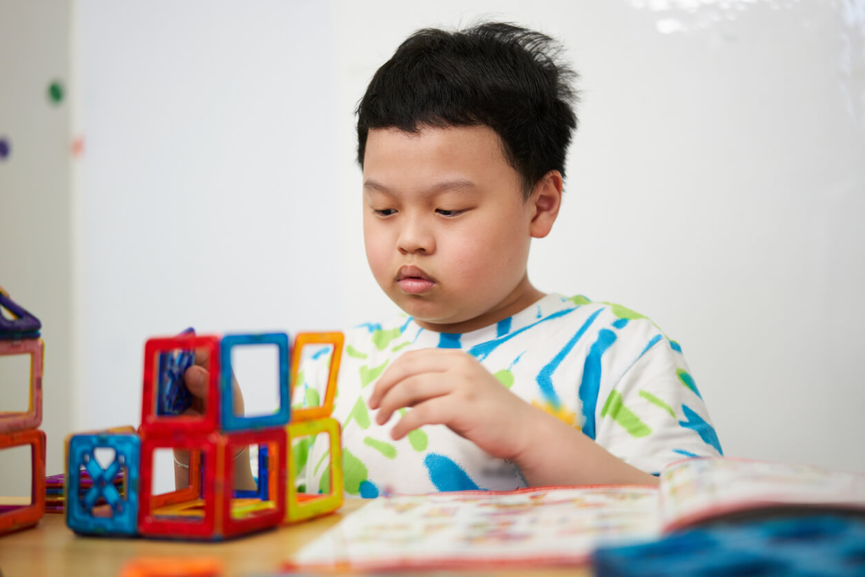 An autistic child building with magnetic tiles.