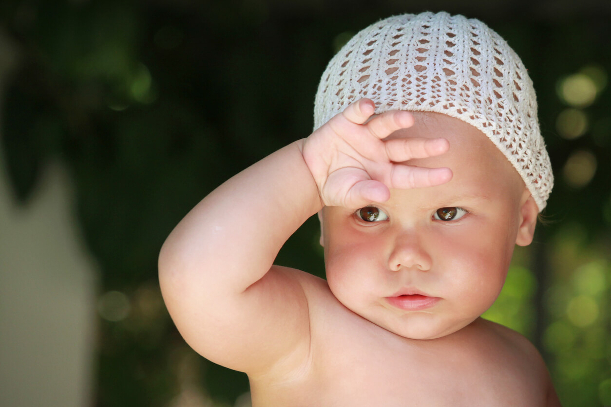 A baby wearing a crochet cap on a hot day.