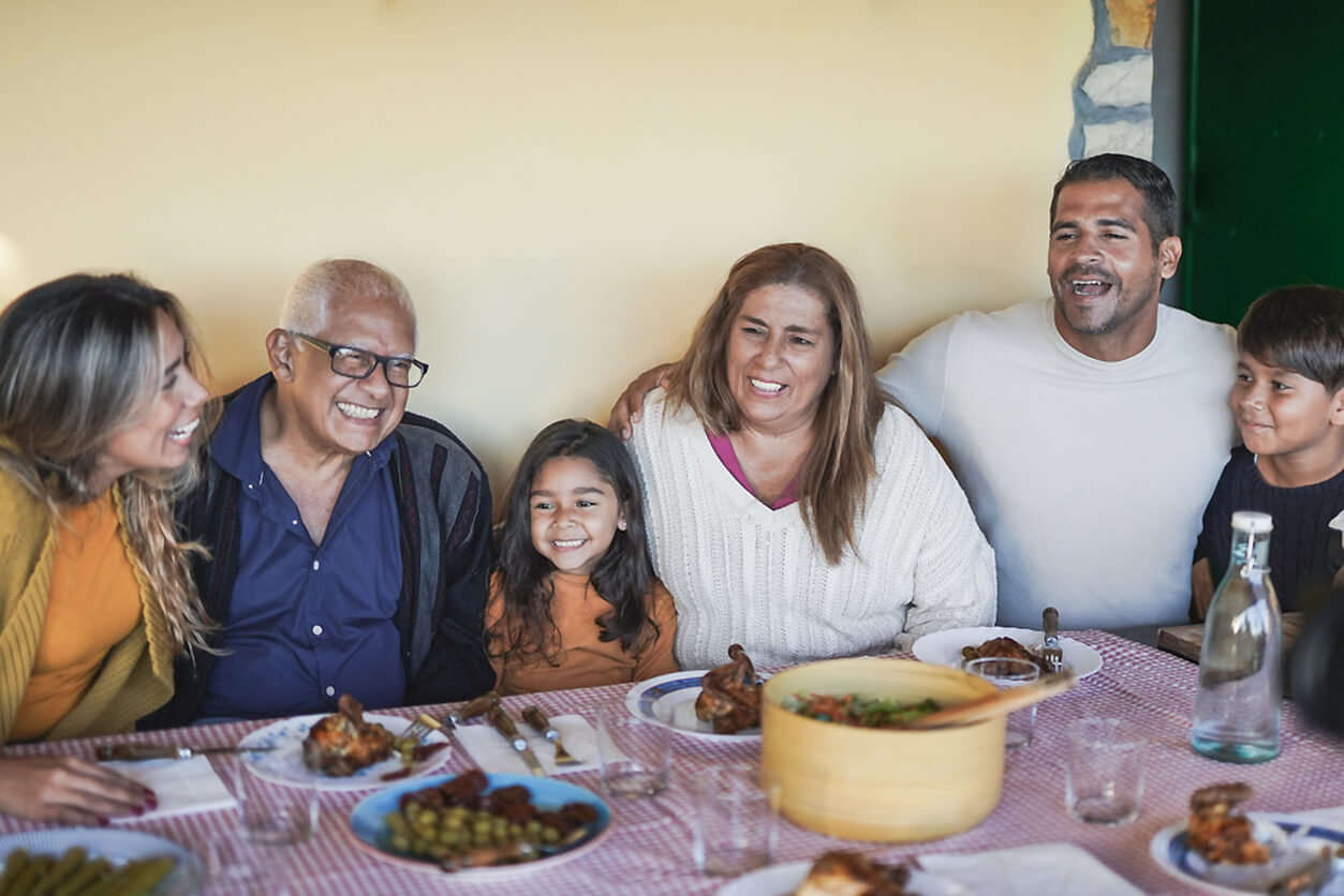 A grateful family sitting around a dinner table smiling.
