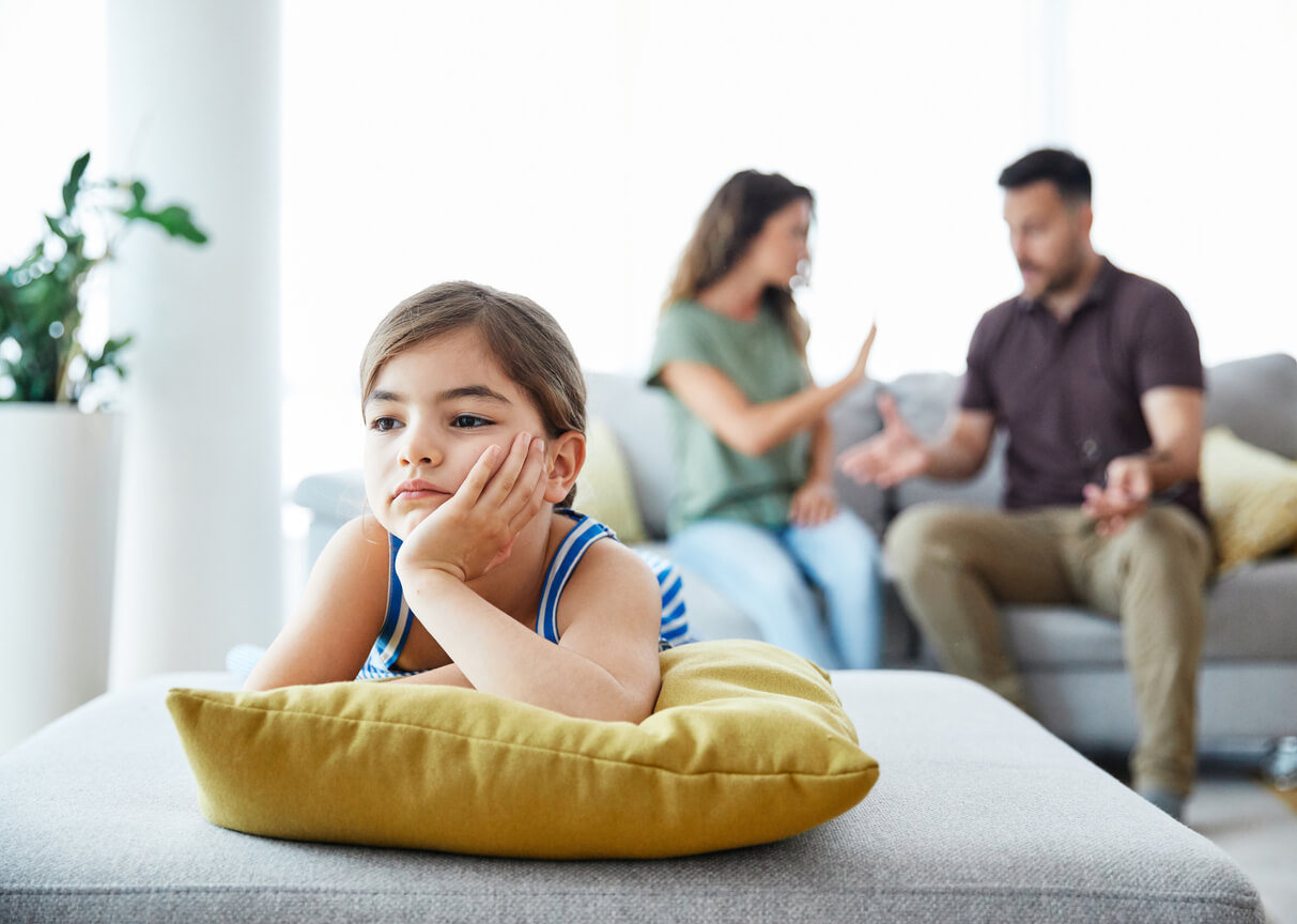 Une jeune fille seule à côté de ses parents qui se disputent;