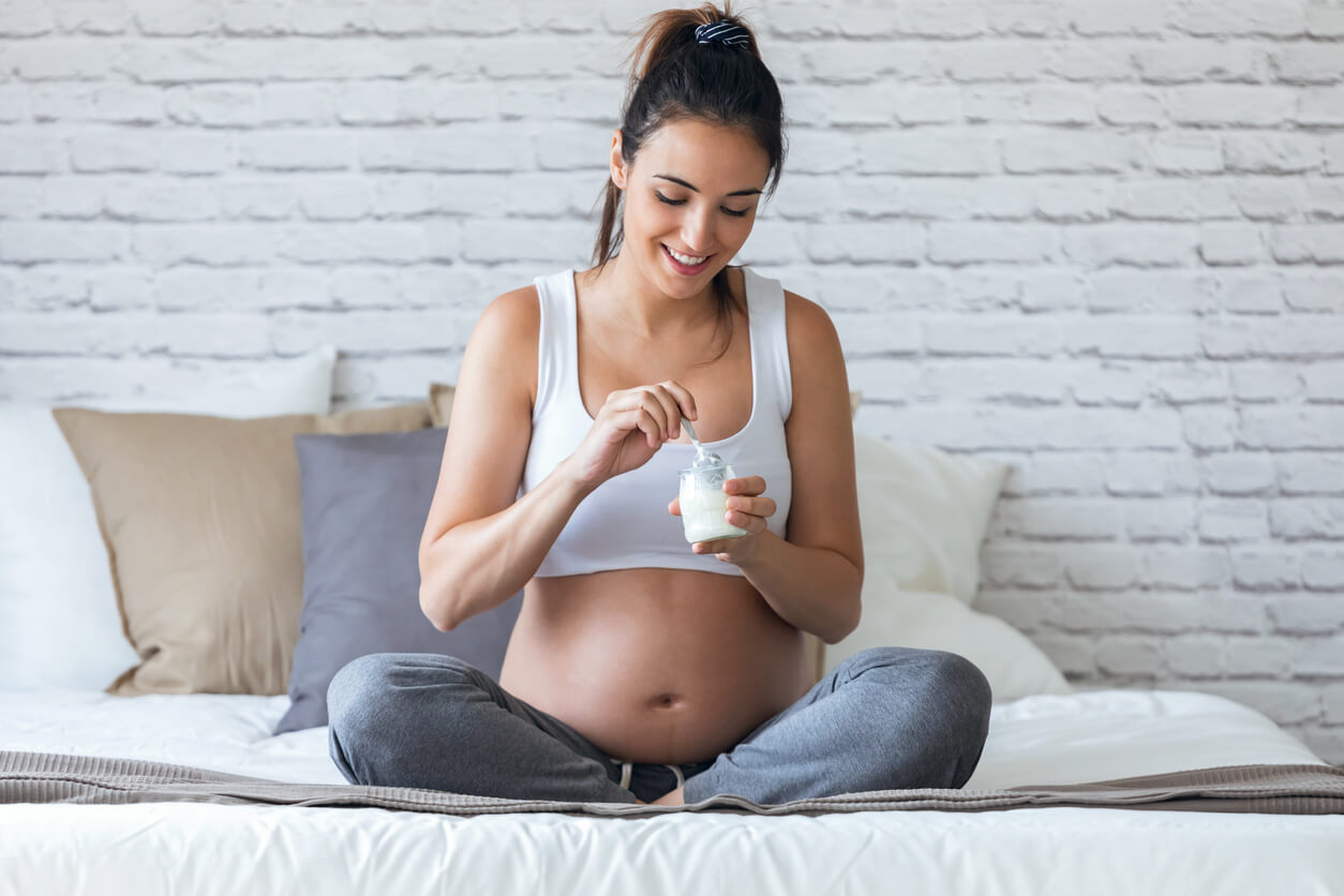 A pregnant woman eating yogurt.