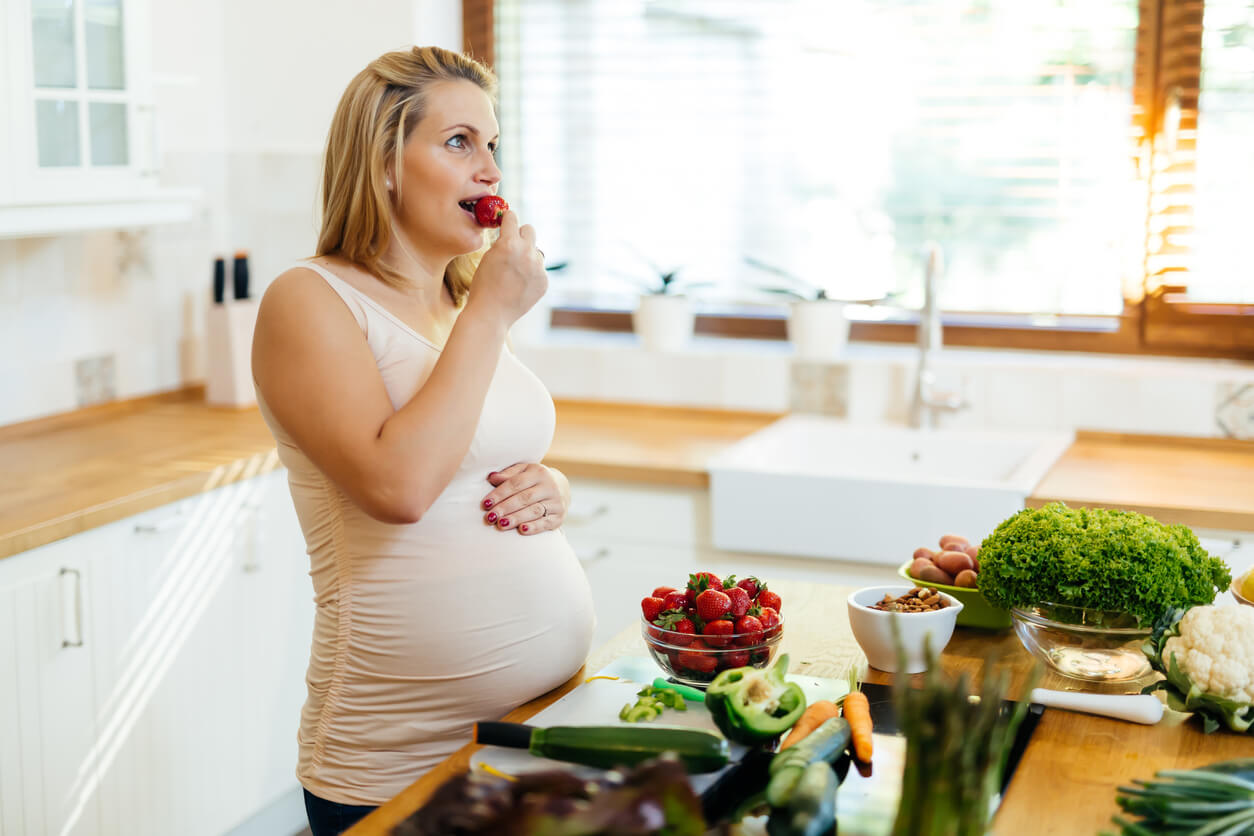 A pregnant woman eating strawberries.