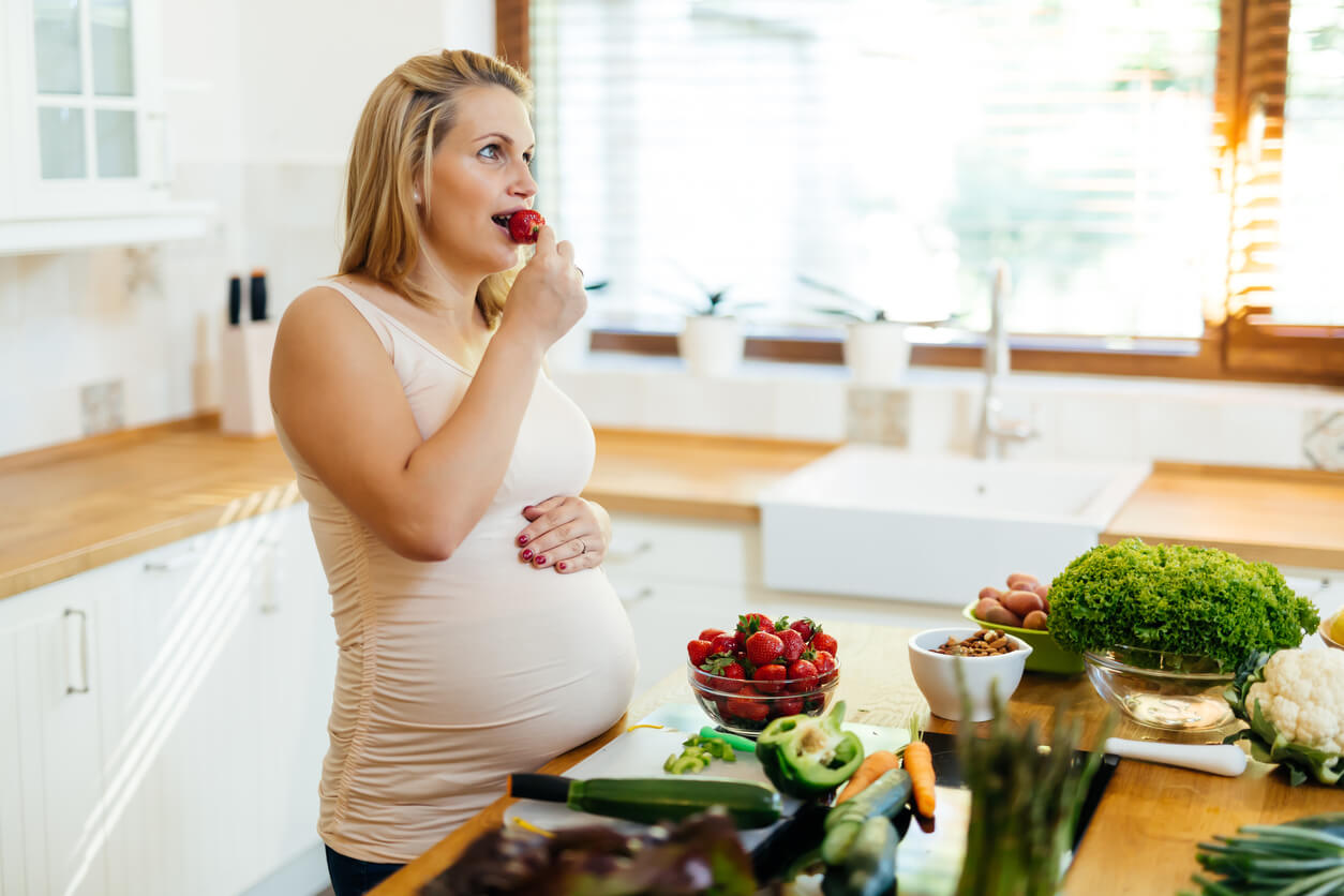 Une femme enceinte qui mange des fraises.