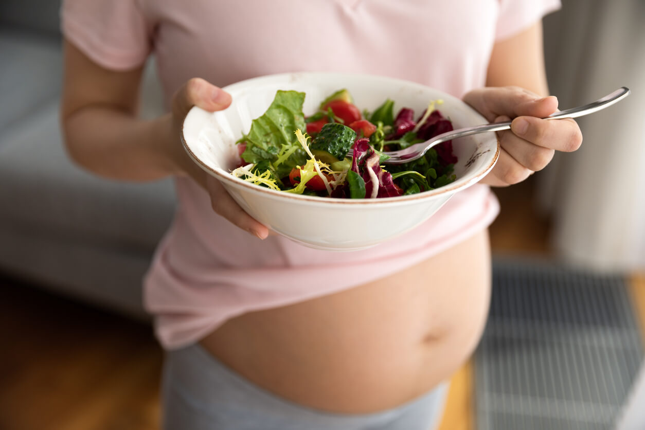 A pregnant woman eating a salad.