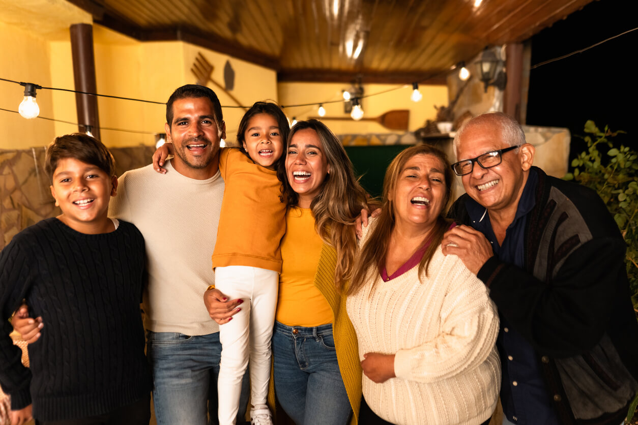 A multigenerational Latino family posing for a photo and laughing.