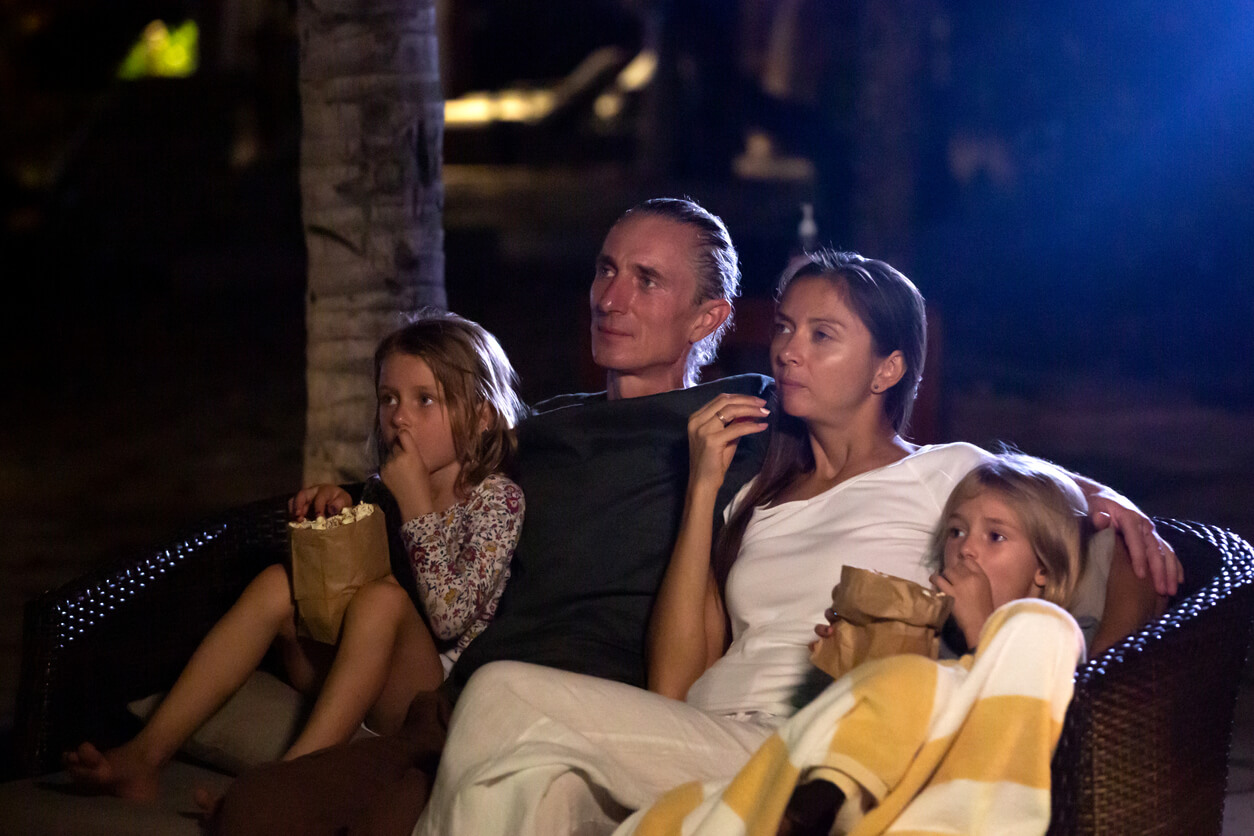 A family watching a film together in their back yard.