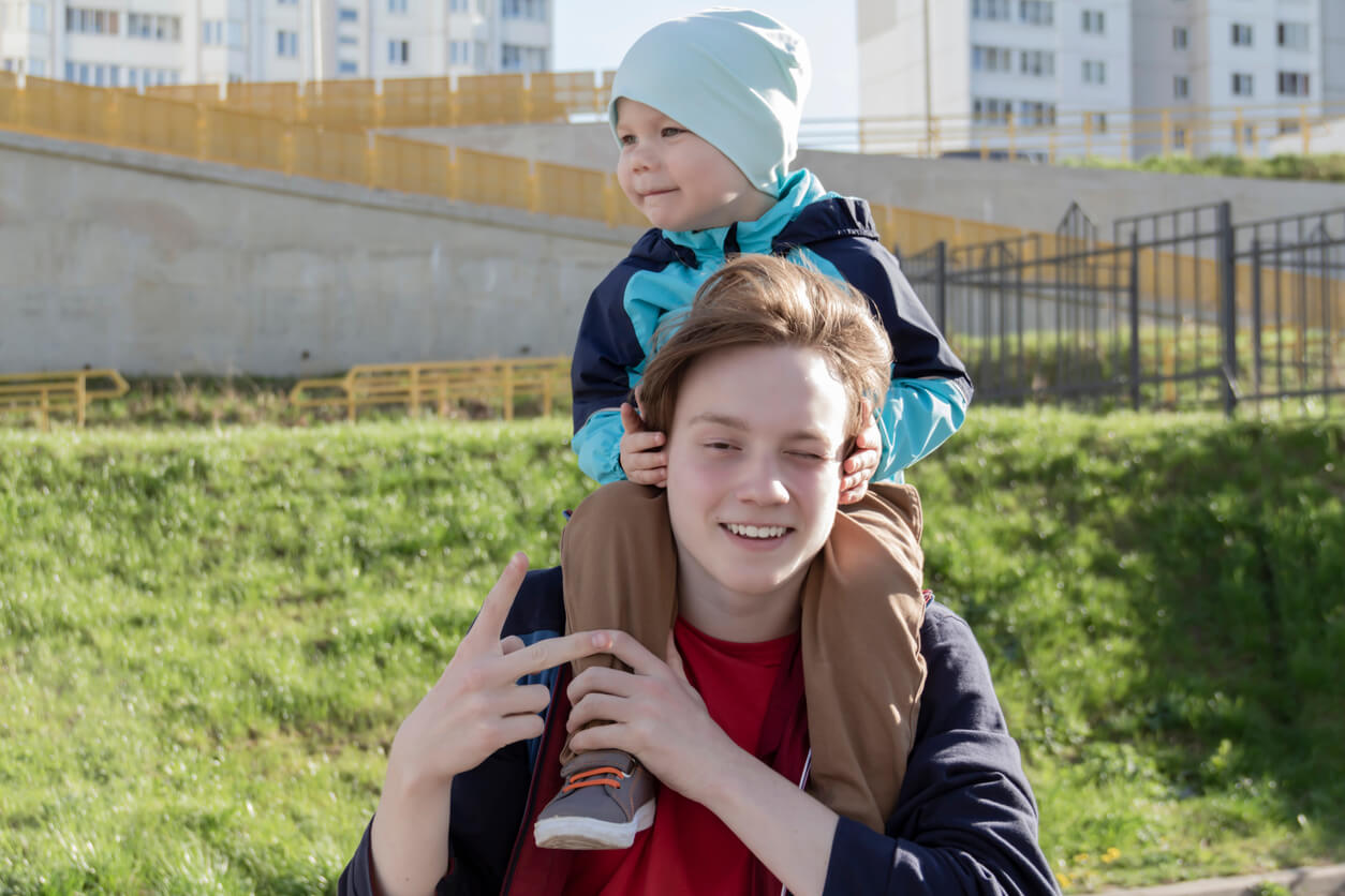 A teenage boy with a toddler boy on his shoulders.