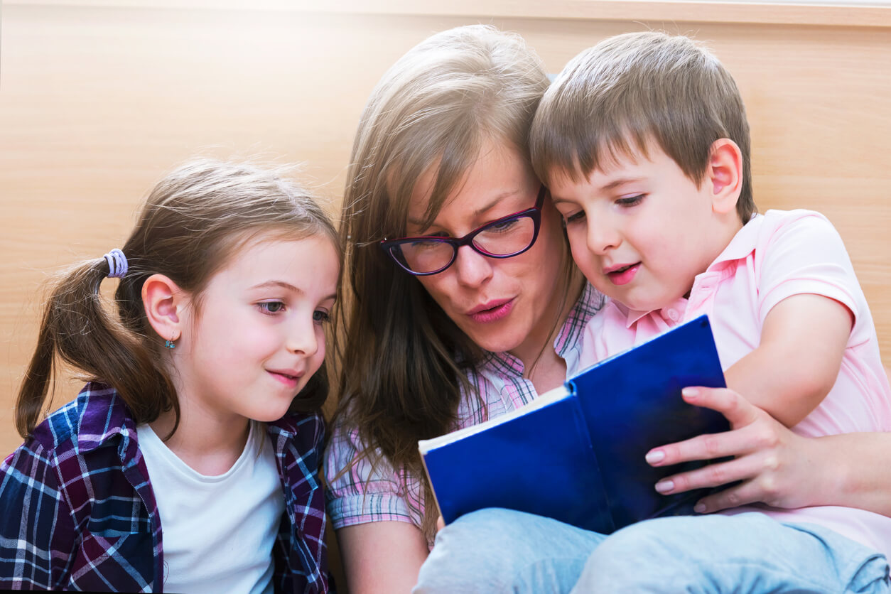 A woman reading a story to a little boy and girl.