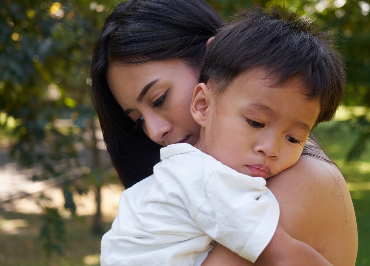 Ett asiatiskt litet barn kramar sin mamma.