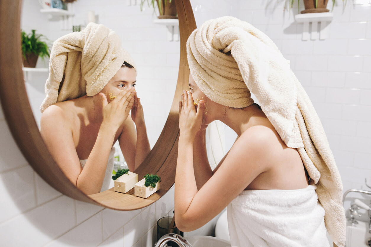 A woman applying an exfoliant scrub to her face.