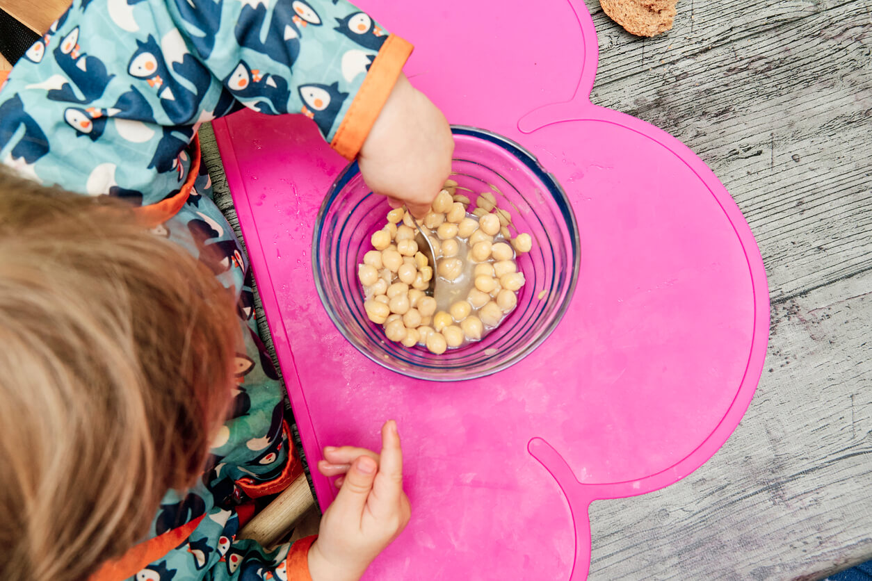 A toddler eating chickpeas.
