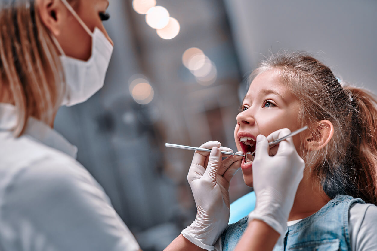 An orthodontist looking at a young girl's teeth.