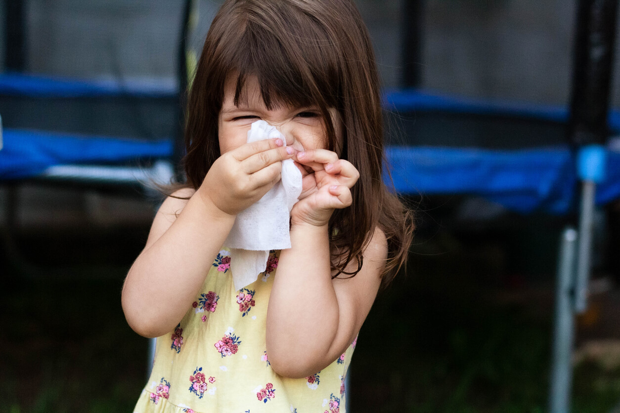 A little girl blowing her nose.
