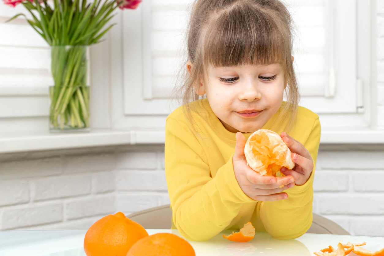 A little girl eating a tangerine.