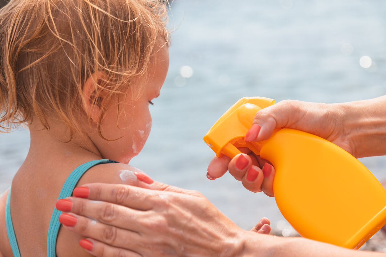 Application de crème solaire sur la peau d'un enfant. 