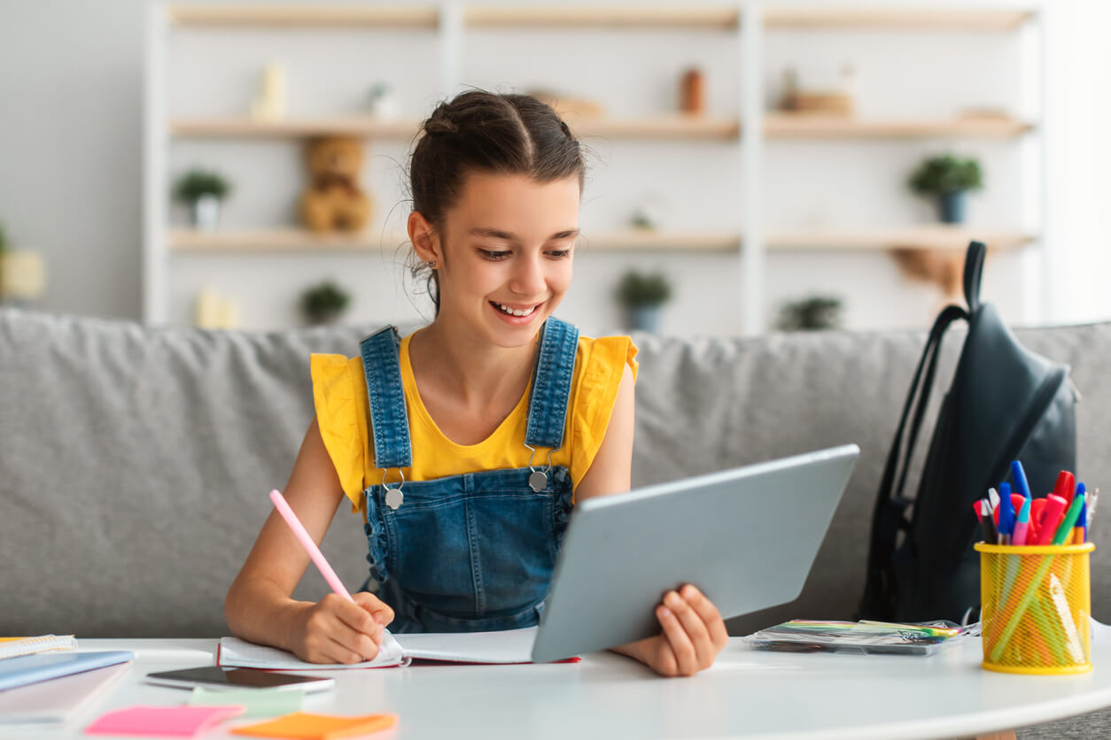 A young child doing schoolwork using a tablet.
