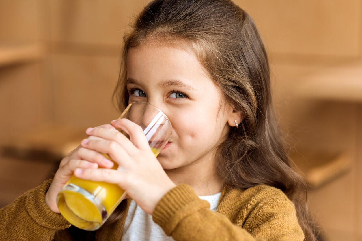 A little girl drinking a glass of juice.