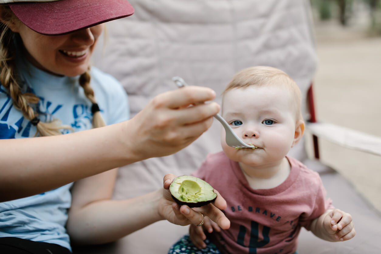 A woman feeding avocado to a baby.