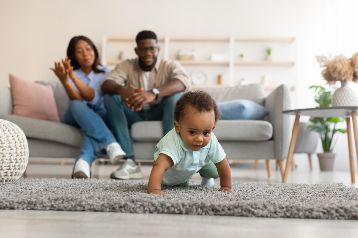 Parents watching from the couch as their baby learns to crawl on his own.