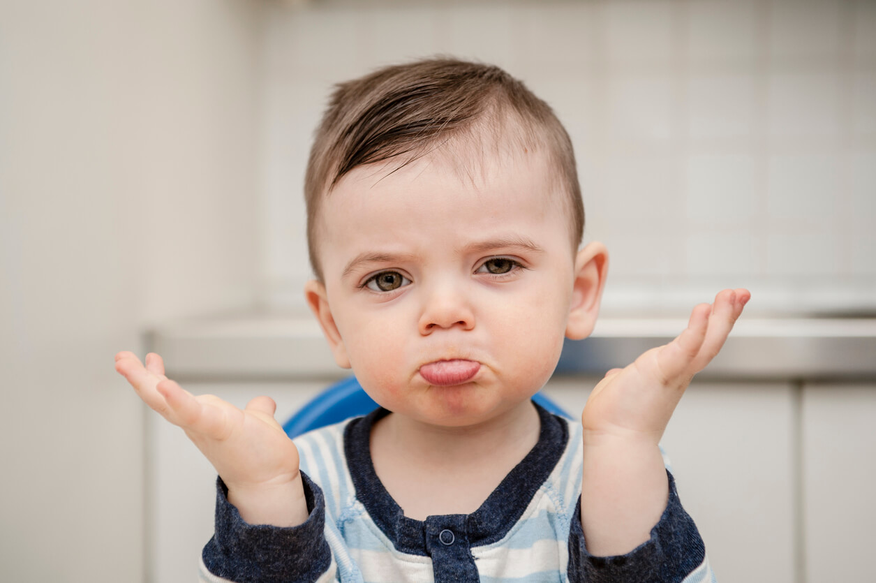 A baby with his hands in the air, showing that he doesn't understand.