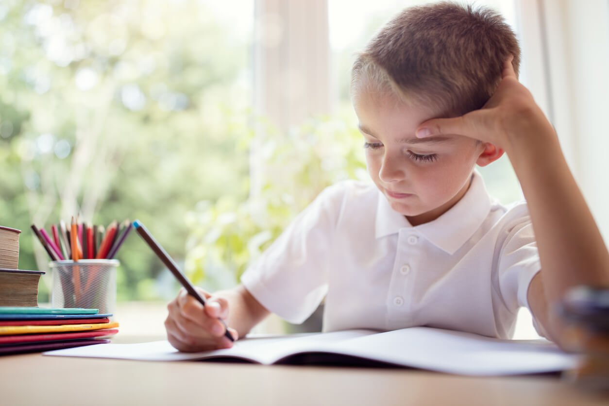 Un enfant qui dessine sur un cahier.