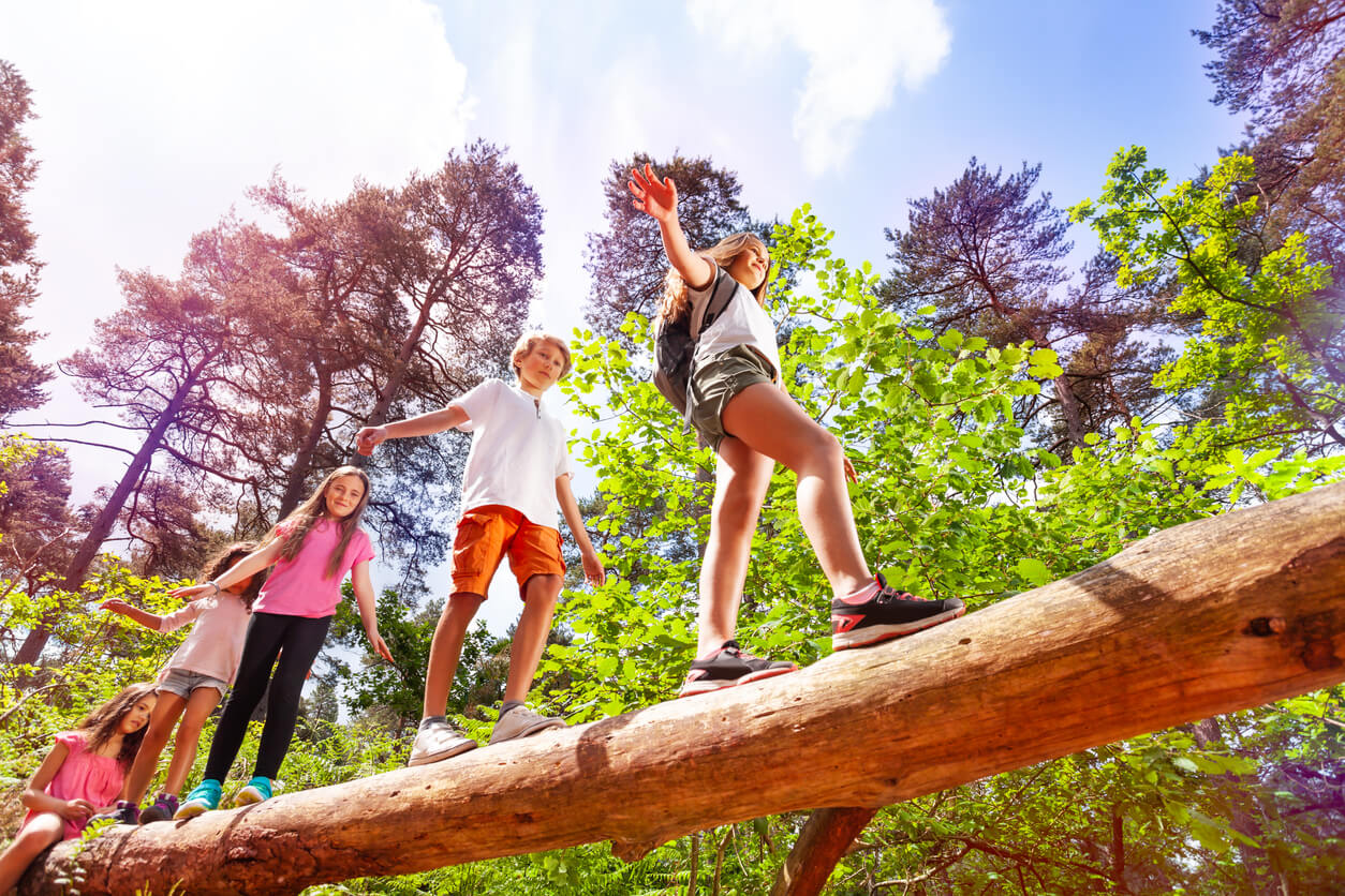 Children balancing on a log during a family hike.