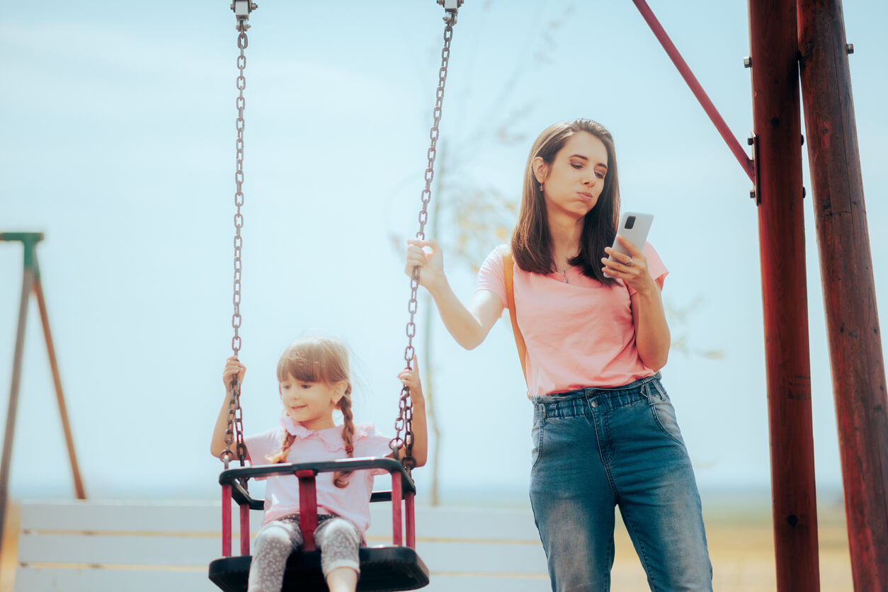 Een moeder heeft meer aandacht voor haar telefoon dan voor haar kind