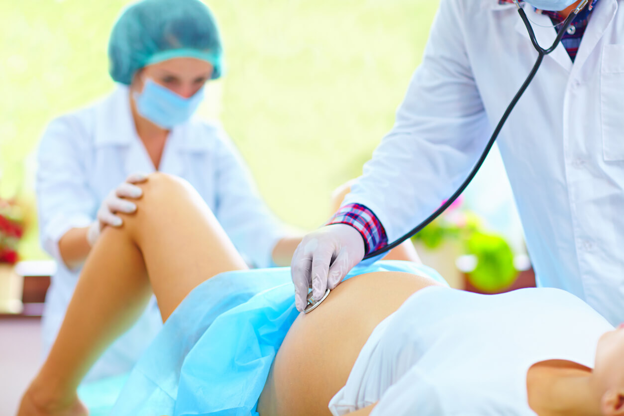 A doctor listening to a mother's belly with a stethescope.