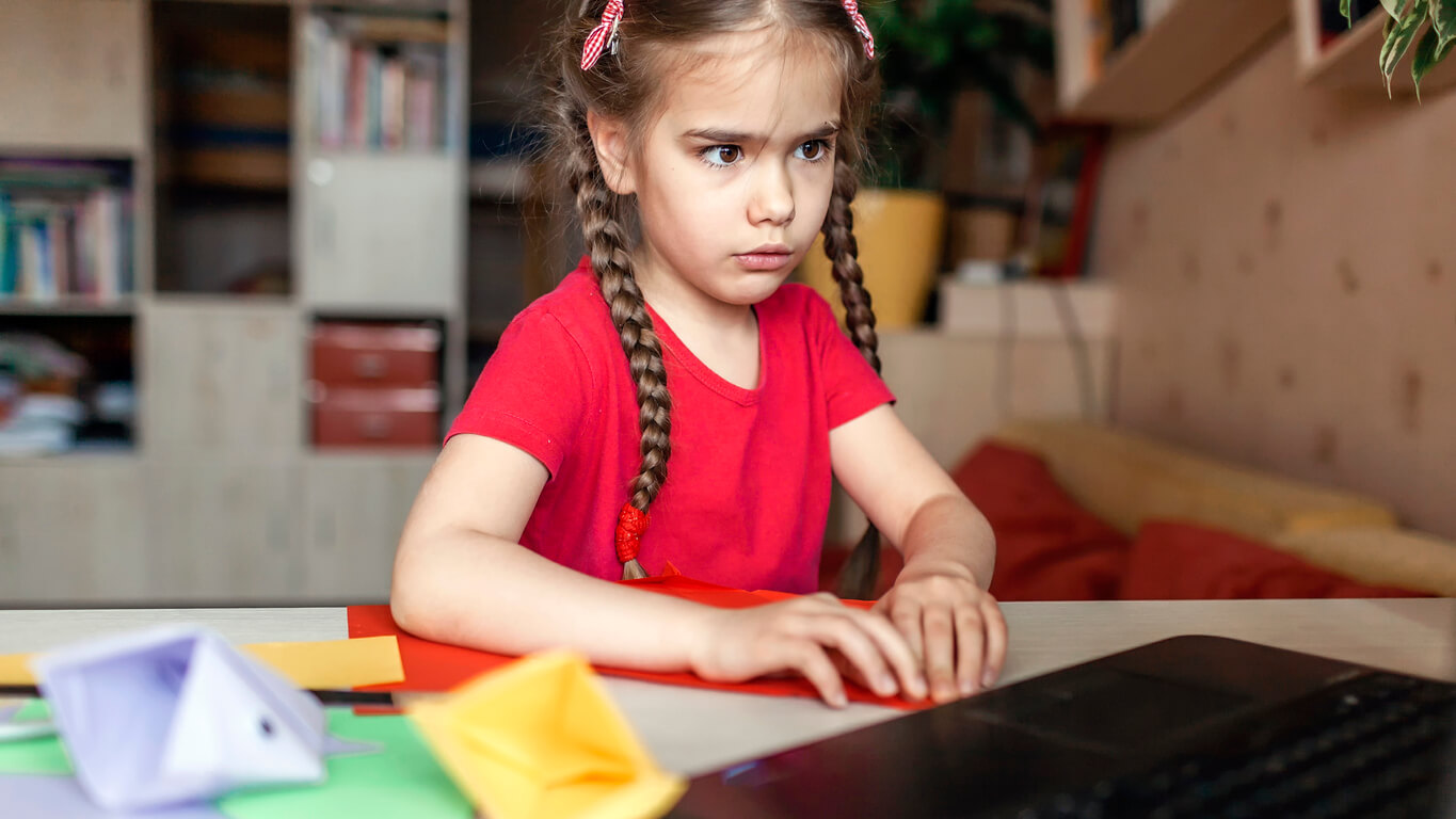 A young girl concentrating on making an origami craft.