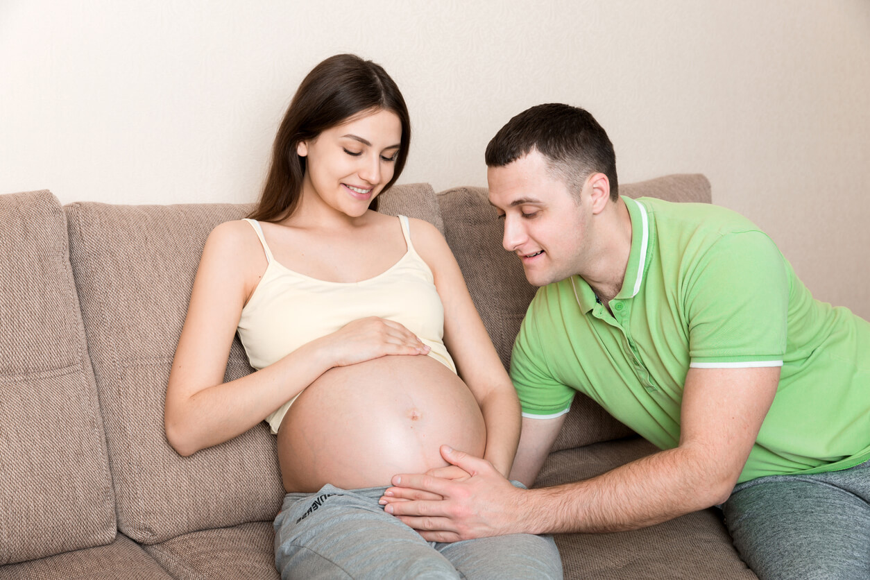 Deux jeunes futurs parents qui parlent au bébé dans le ventre.