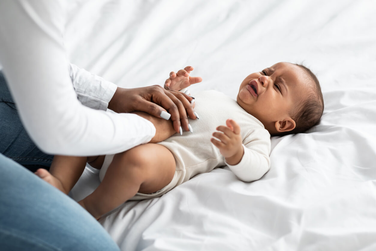 A black mother massaging her baby's belly.